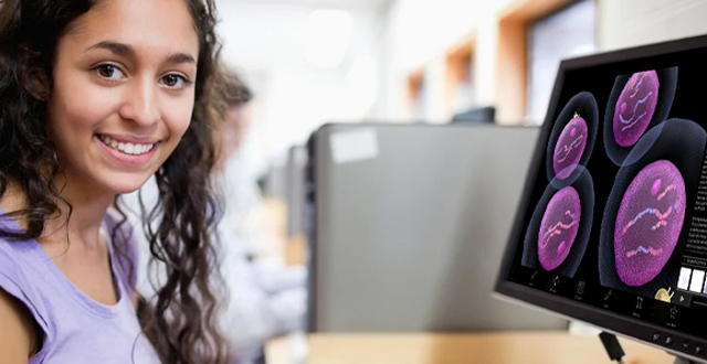 Student in a classroom with computer showing cells in Visible Body